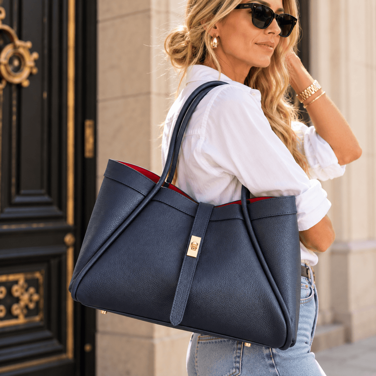 Frau in weißer Bluse trägt die dunkelblaue Leder-Handtasche Bag Nova über der Schulter