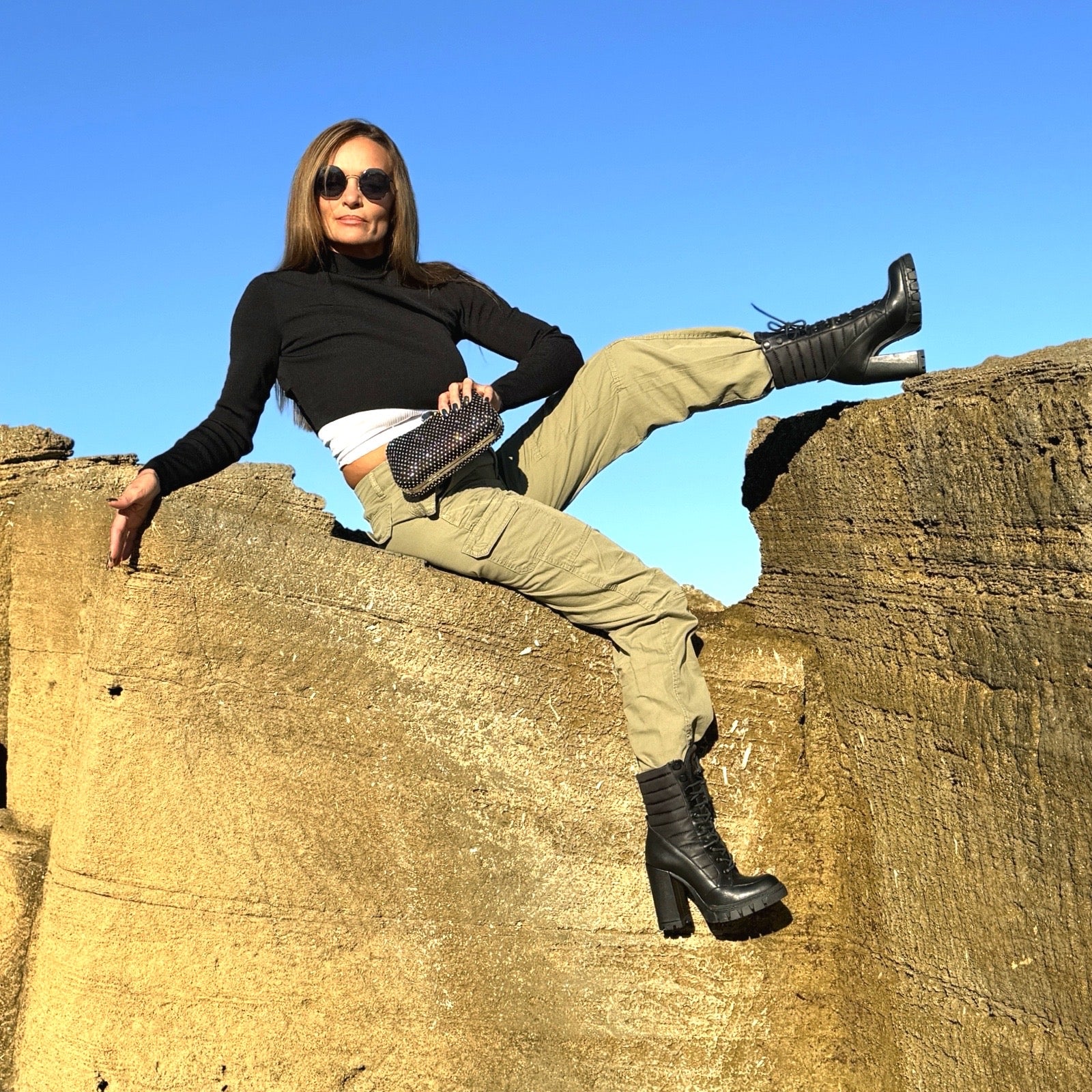 Rachel Boots – LiBEAU Damen trägt schwarze Plateau Stiefeletten zu Cargo-Hose und schwarzem Rollkragen auf antiken Ruinen, abenteuerlicher selbstbewusster Editorial Look | LiBEAU
