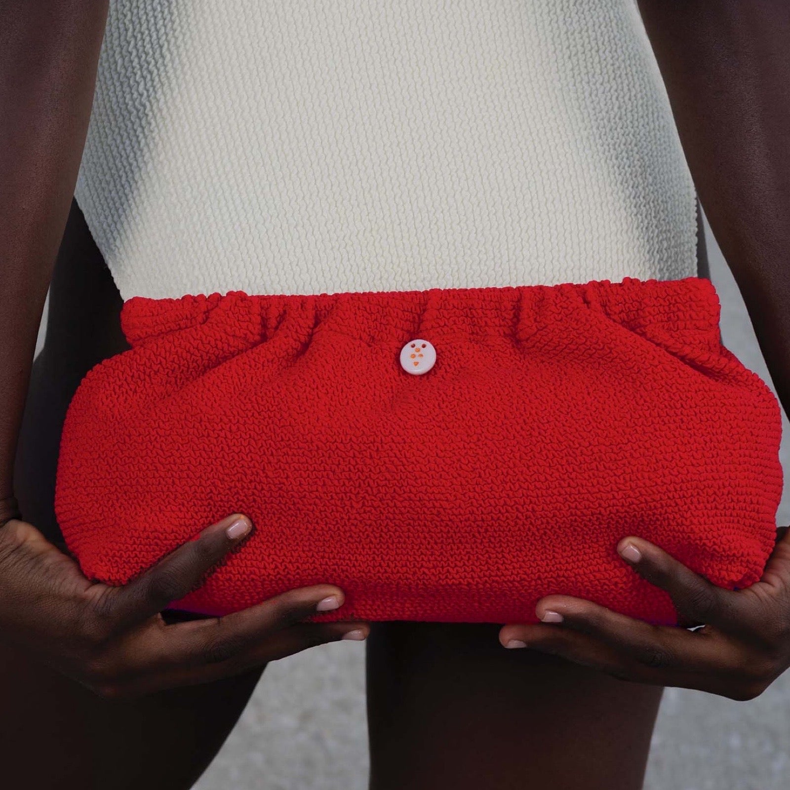 Swim Clutch Crinkle Red – Model hält rote Crinkle Strandtasche, sommerlicher Look | LiBEAU
