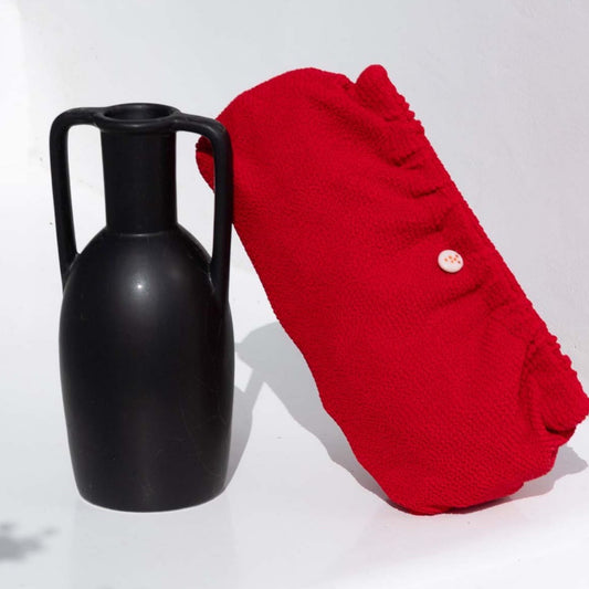 Swim Clutch Crinkle Red – Rote Crinkle Strandtasche neben Vase, Lifestyle-Ansicht | LiBEAU
