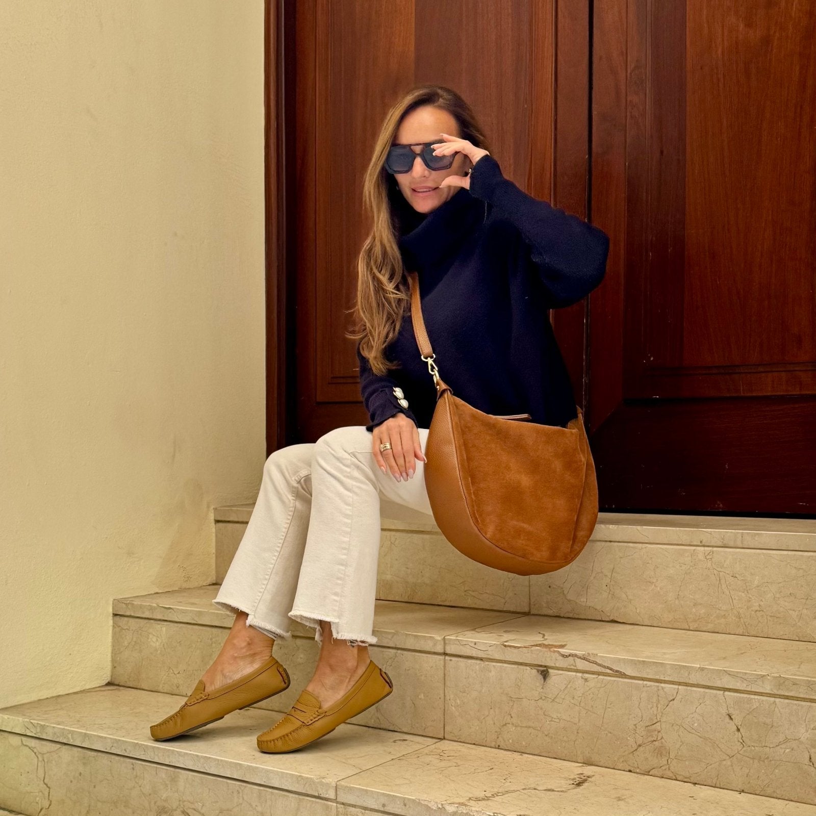 Sienna Mokassin – LiBEAU Damen trägt Cognac Caramel Leder Penny Loafer zu weißen Jeans und marineblauem Rollkragen auf Marmorstufen, zeitloser eleganter City Editorial Look | LiBEAU
